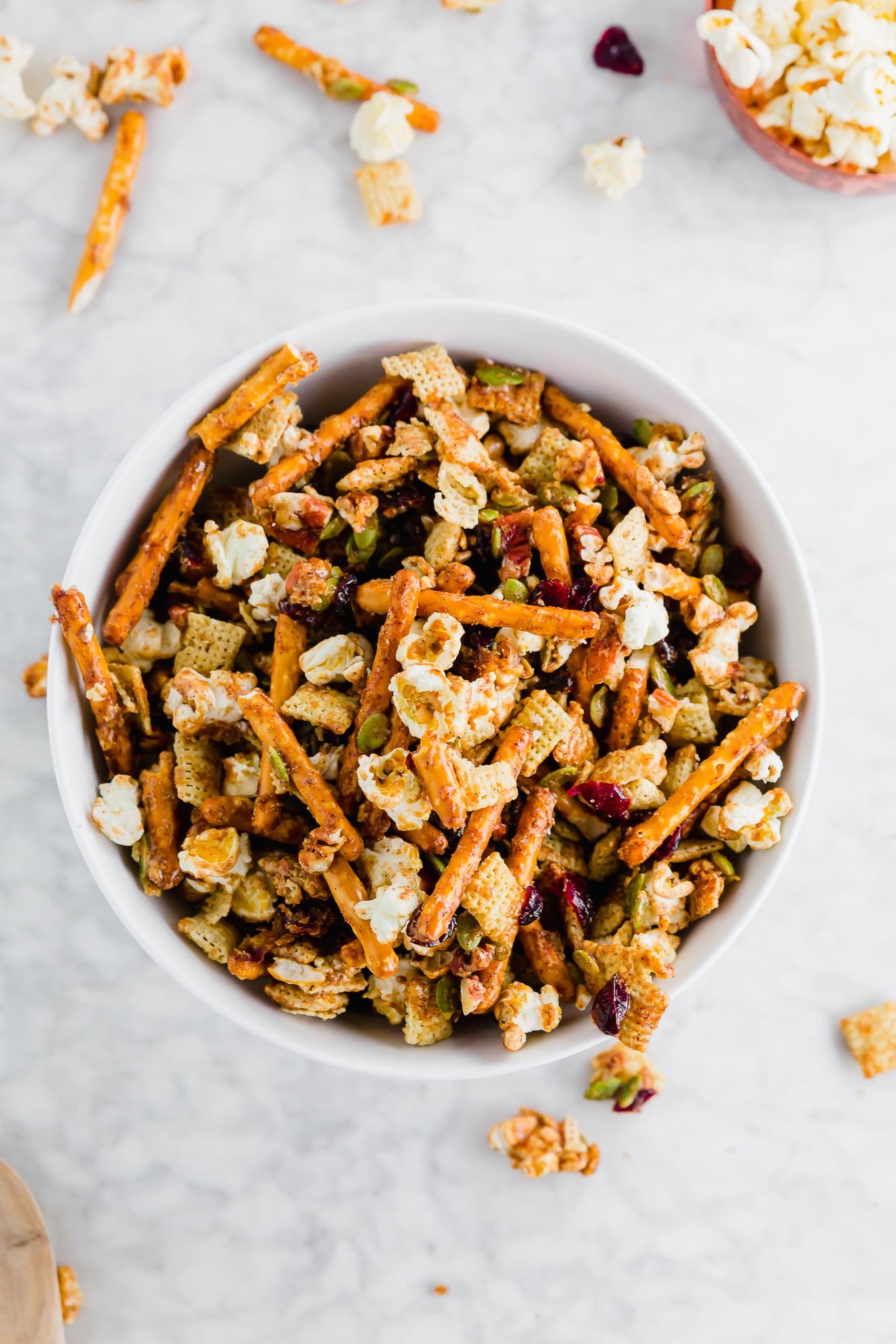 A photo of maple cayenne snack mix with popcorn, gluten-free pretzels, pepitas, pecans, and chex mix.