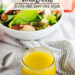 A jar of homemade apple cider vinaigrette with an apple salad in the background and a bottle of Bragg's apple cider vinaigrette.