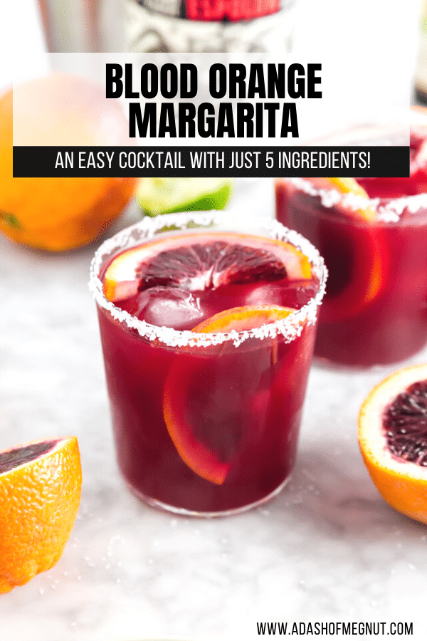 A photo of a blood orange margarita on the rocks with a salted rim and sliced blood oranges. 