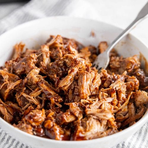 A photo of a large bowl with shredded BBQ pulled pork and a fork.