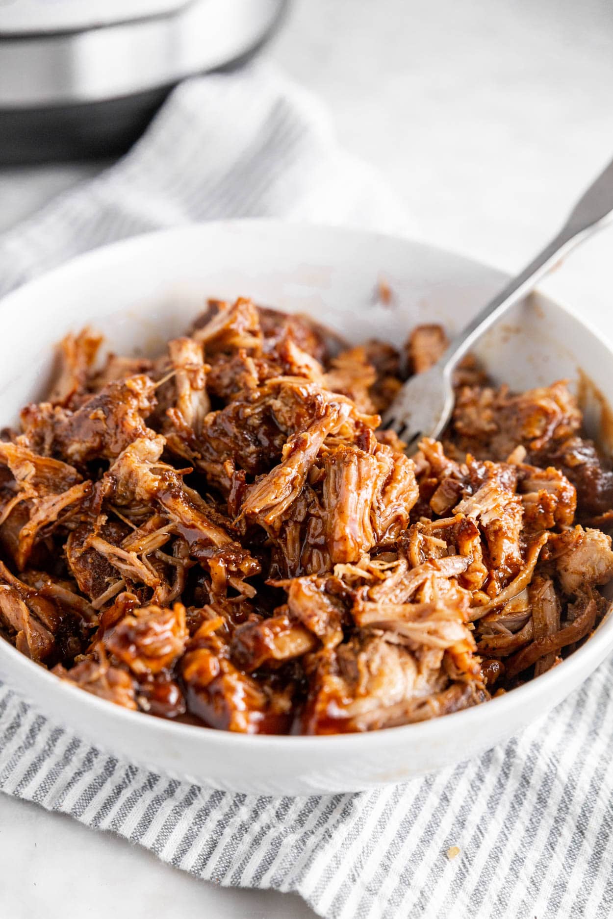 A photo of a large bowl with shredded BBQ pulled pork and a fork.