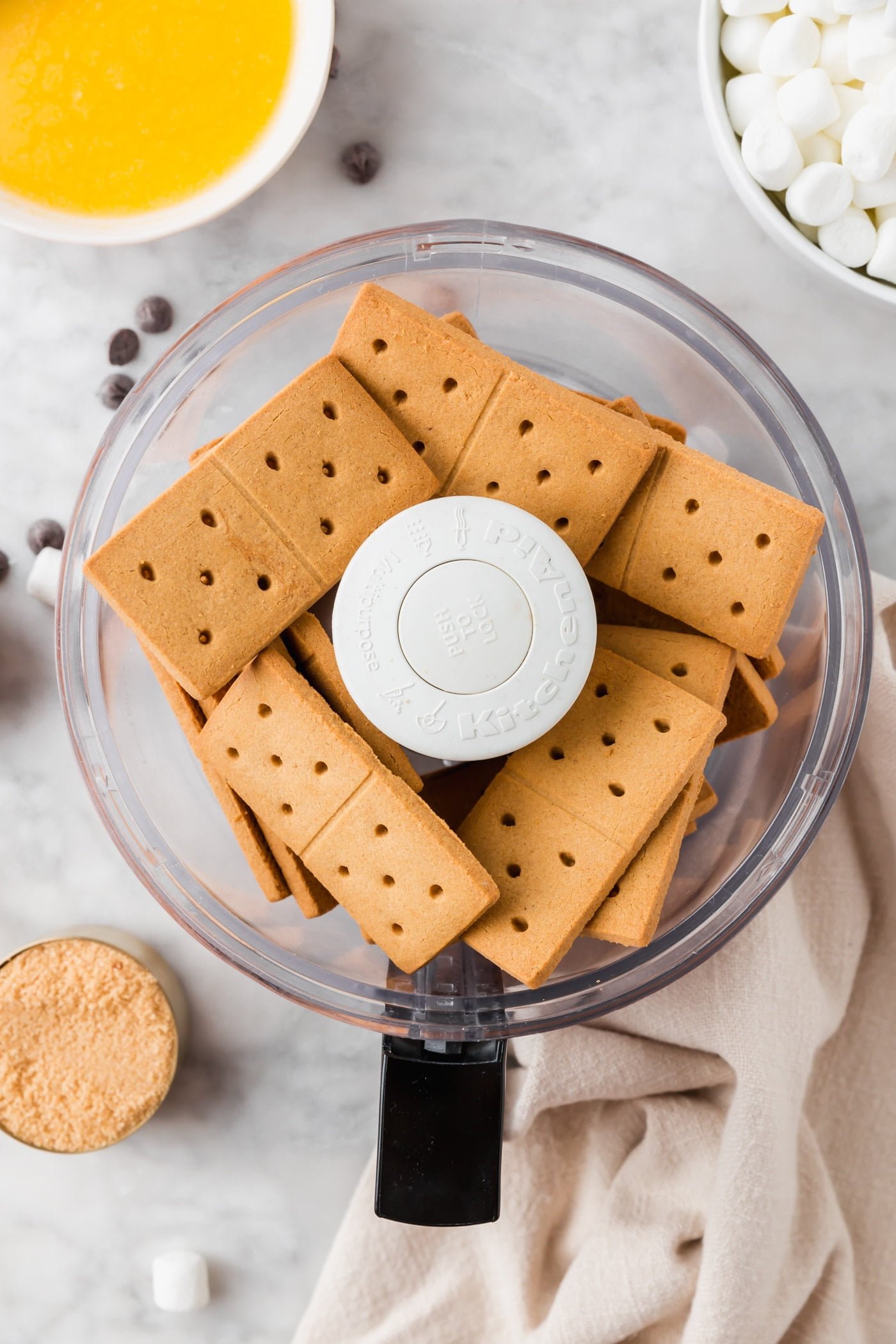 A food processor with gluten-free graham crackers in it.