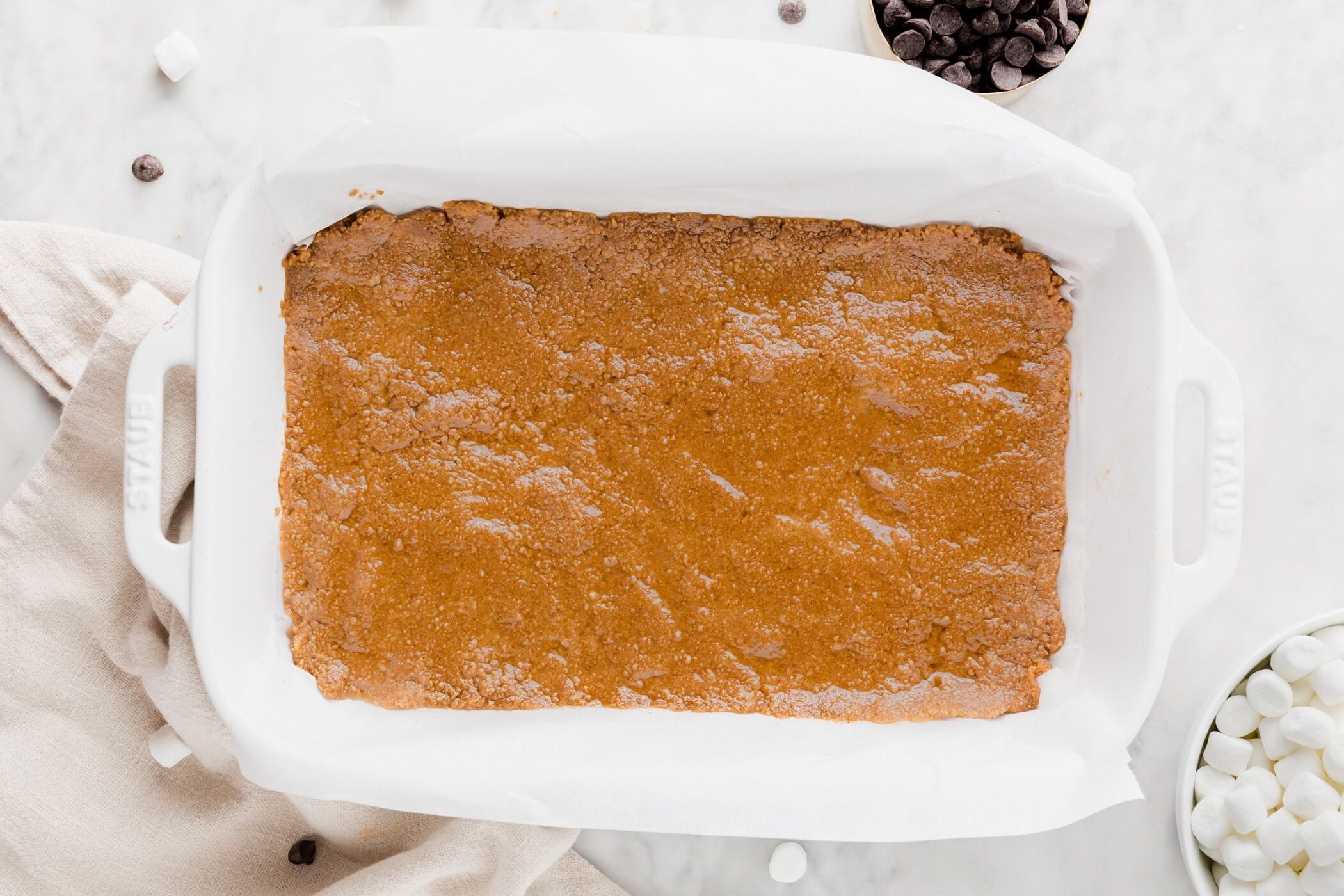 Gluten-free graham cracker crust pressed into the bottom of a baking dish lined with parchment paper.