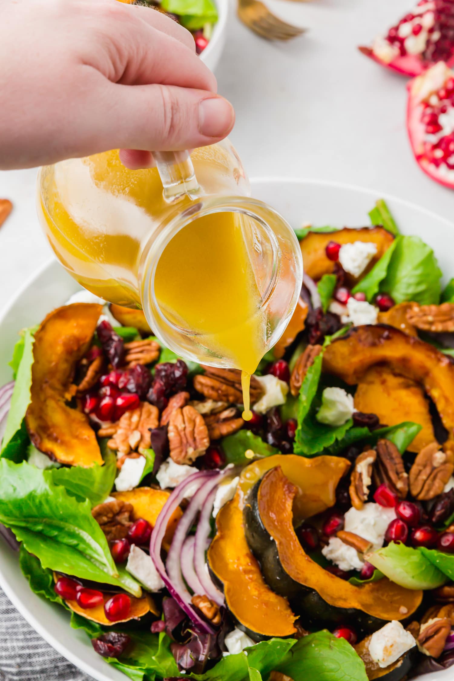 Apple cider vinaigrette being poured on acorn squash salad.