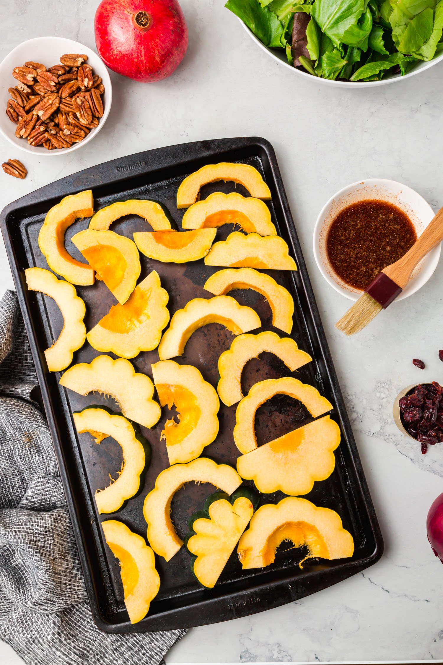 A layer of sliced acorn squash on a baking sheet. 