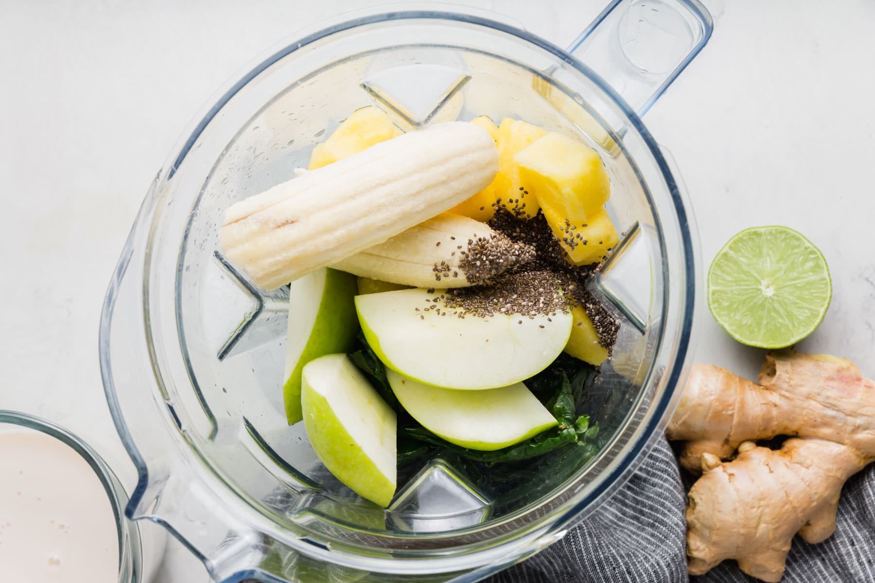 A blender with banana, apple, chia seeds, and pineapple.