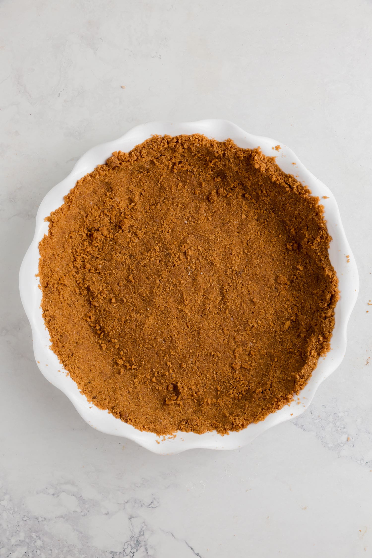 A pie tin with gluten-free graham cracker crust in it.