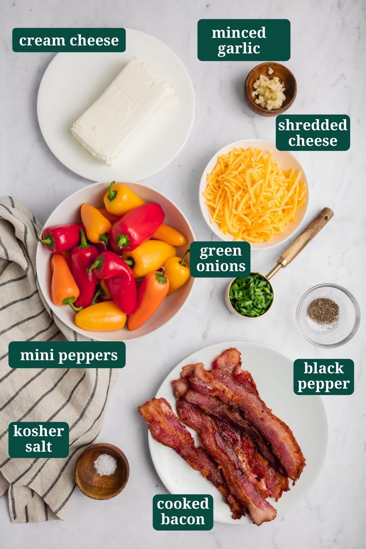 An overhead photo of ingredients for mini stuffed peppers: cream cheese, minced garlic, black pepper, green onion, bacon, mini stuffed peppers, salt.