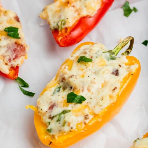 A photo of a yellow mini pepper stuffed with a hot cream cheese and bacon mixture and topped with fresh parsley.