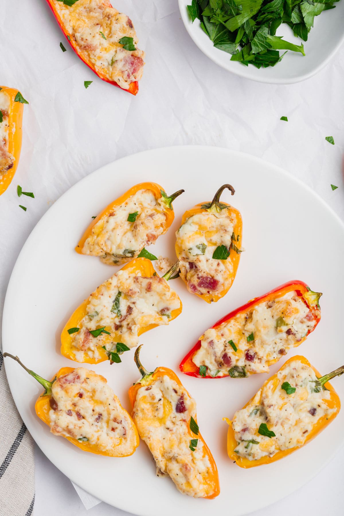 An overhead photo of a plate with seven yellow and red mini peppers stuffed with bacon cheddar cream cheese mixture.