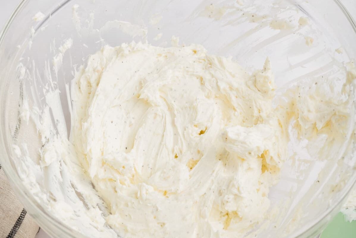 A glass bowl with softened cream cheese that has been mixed.