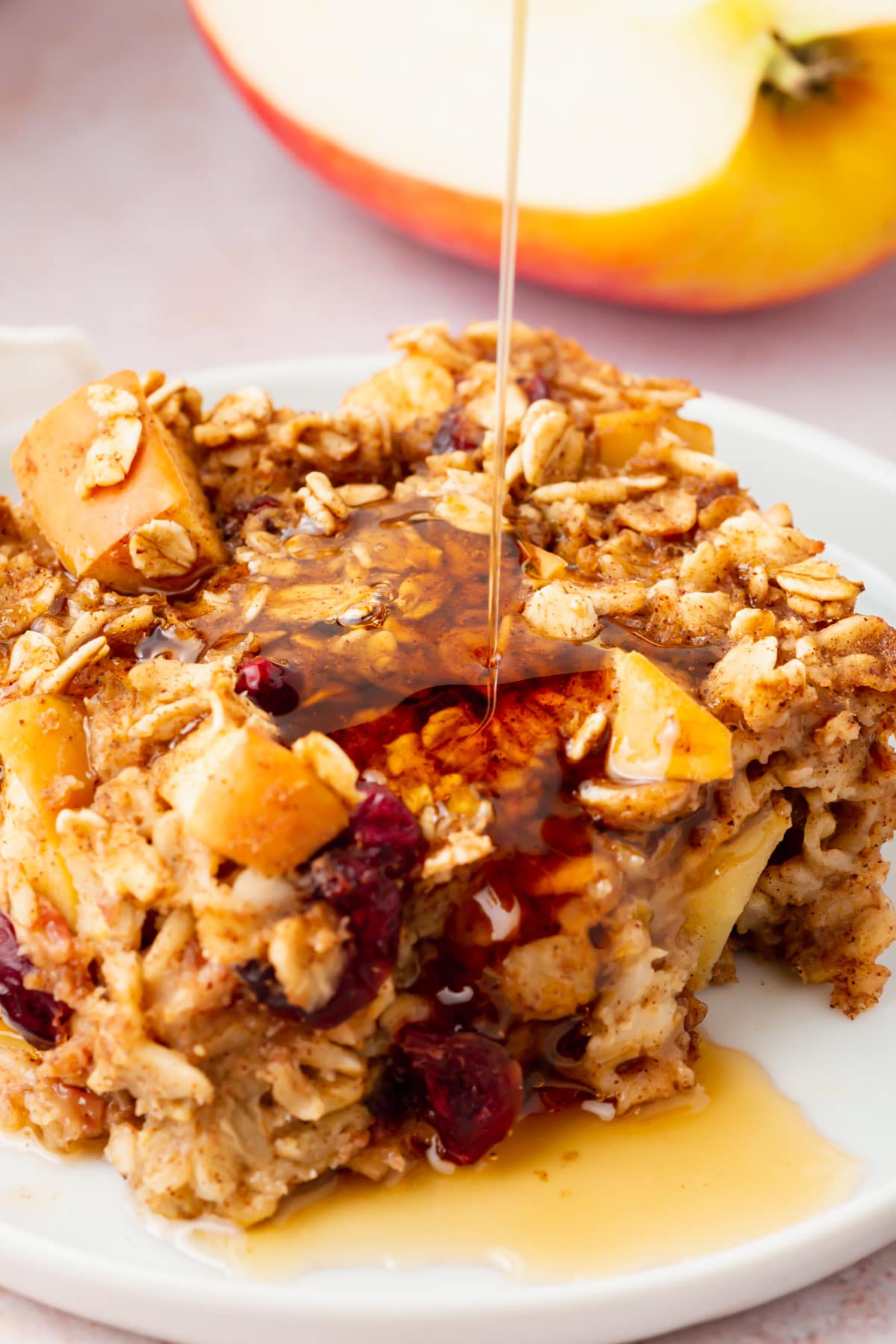 A close-up of a square of gluten-free vegan apple baked oatmeal on a plate drizzled with honey.