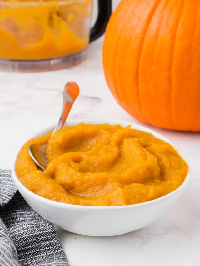 A bowl of pumpkin puree with a pumpkin in the background.
