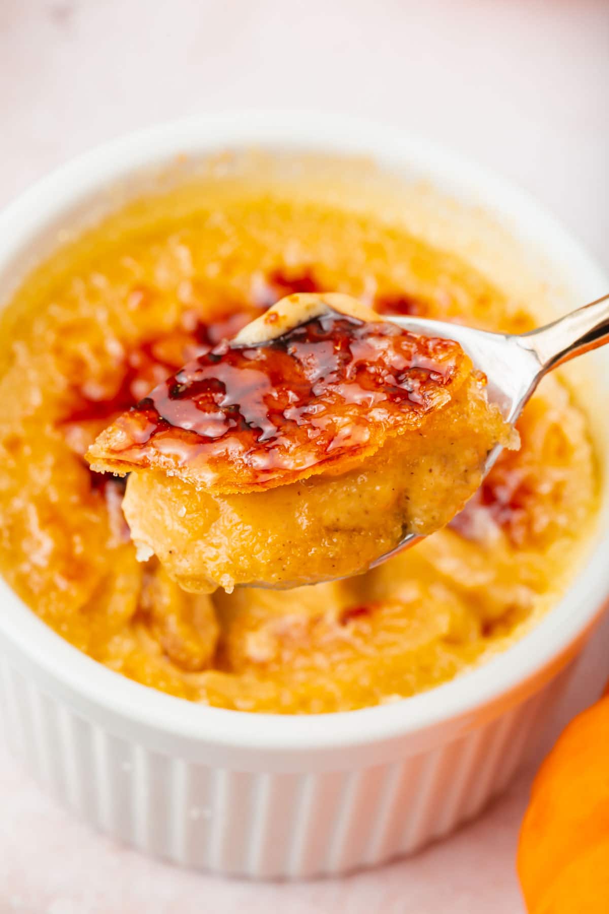 A spoonful of pumpkin crème brûlée with a creamy filling and crackle crust topping.