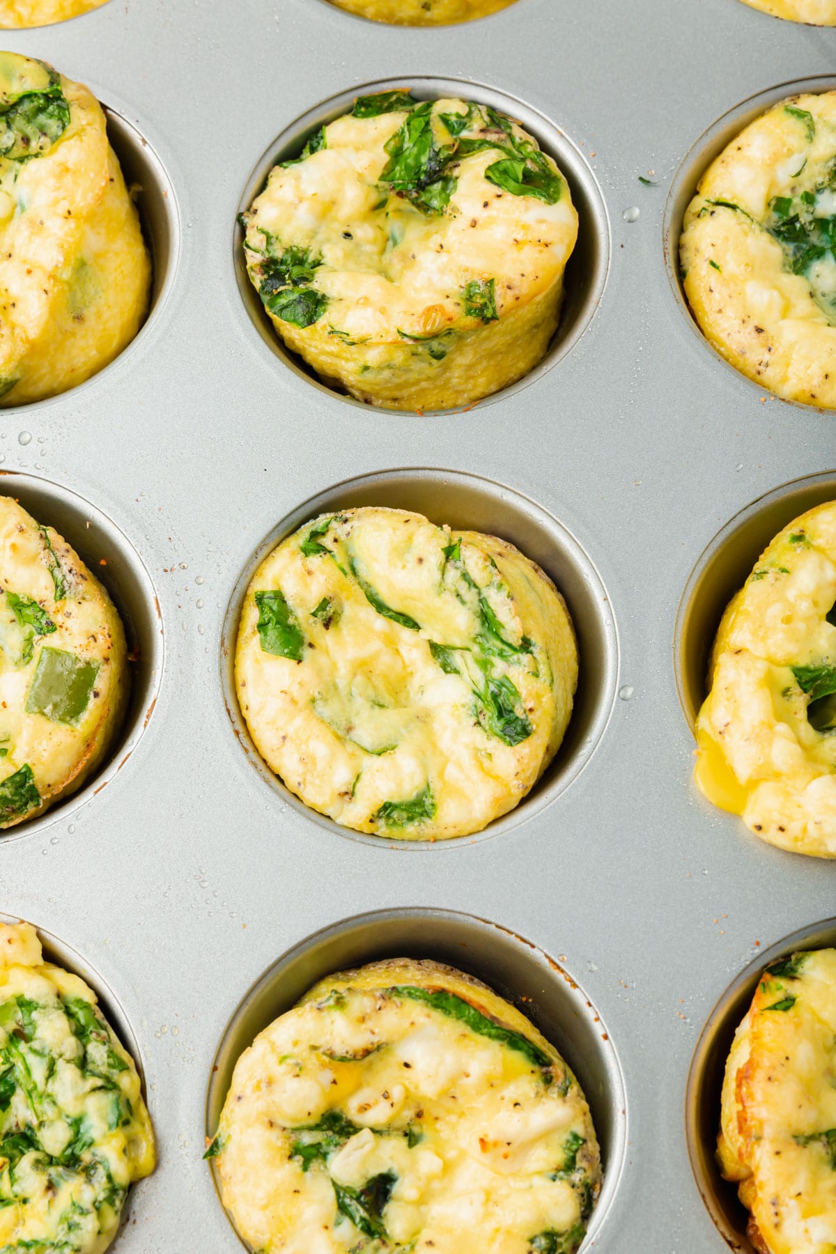 A muffin tin filled with spinach feta egg muffins.