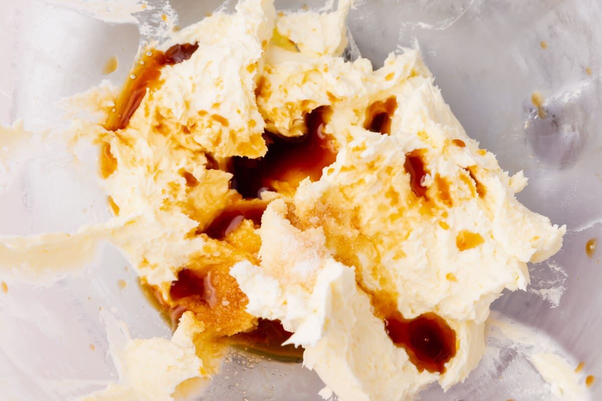 A mixing bowl with creamed butter, salt and vanilla extract in it.