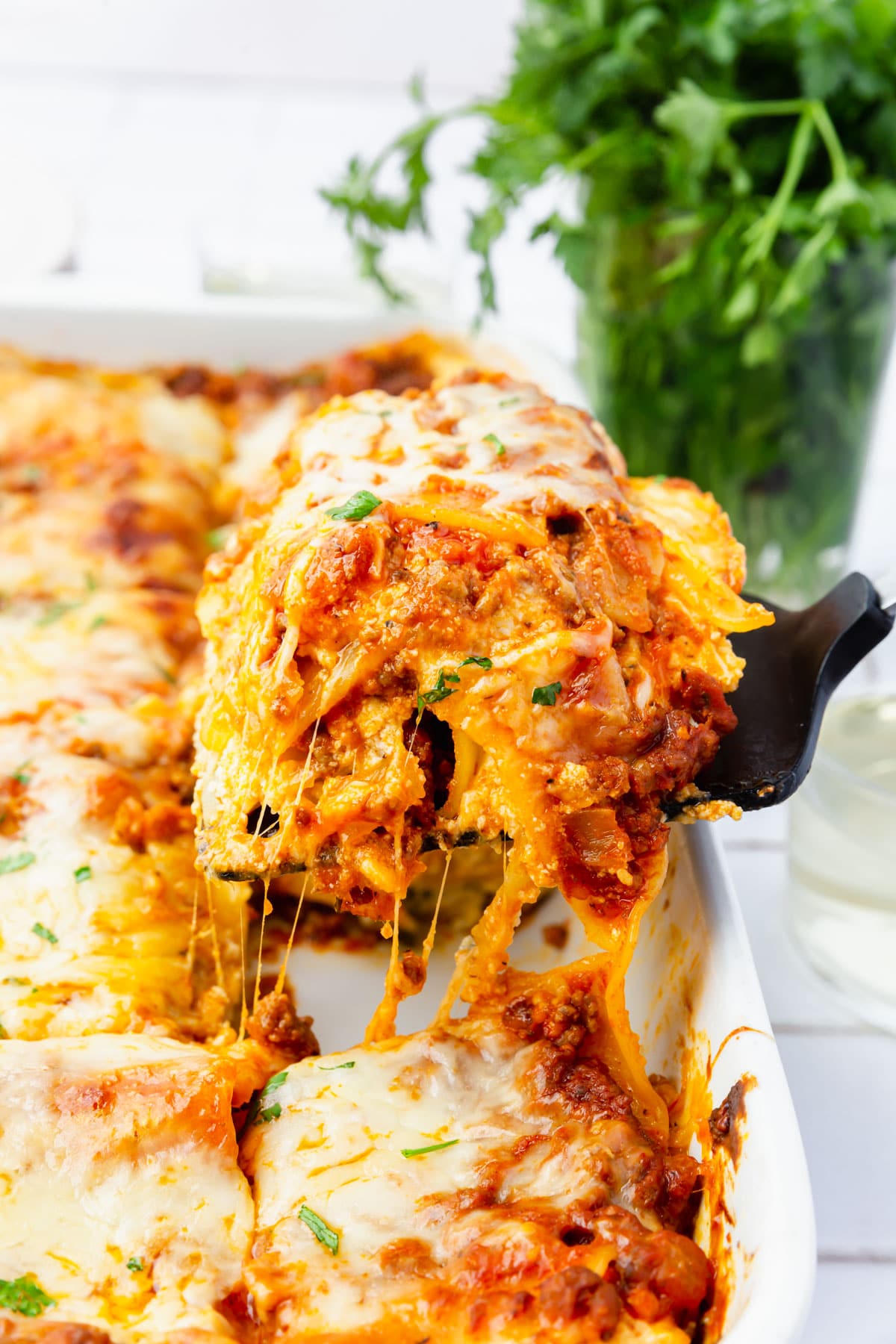 A square of gluten-free beef lasagna being lifted out of a dish on a spatula.