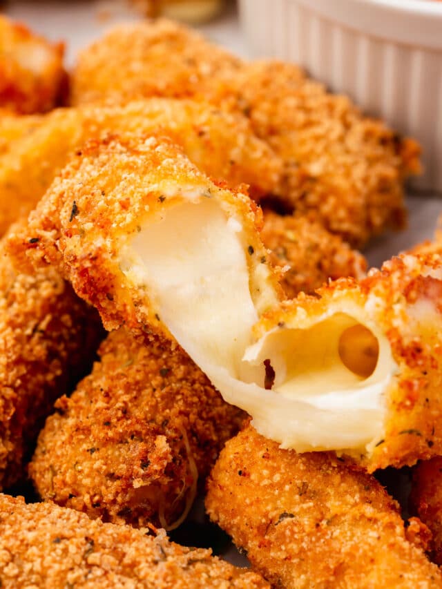 A close-up of a gluten-free mozzarella stick broken open to show the oozing cheese.