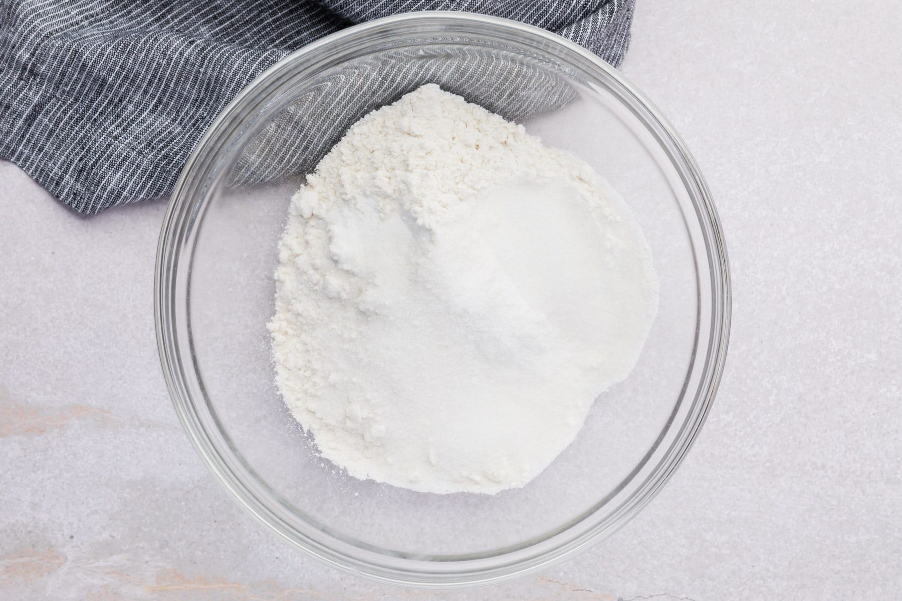 Gluten-free flour blend and granulated sugar in a glass bowl.
