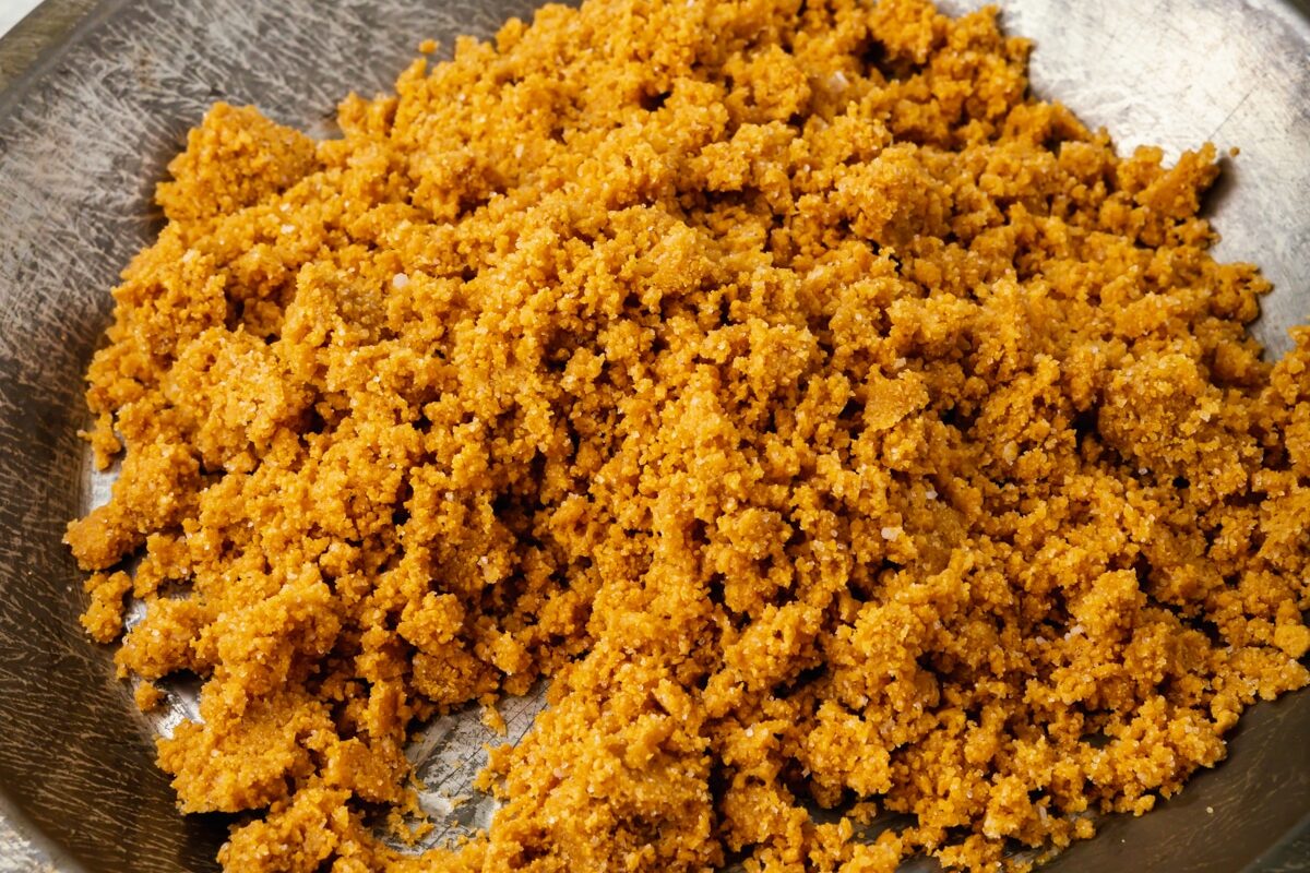 Coarse mixture of crumbled gluten-free graham cracker and melted butter in a metal pie tin before pressing into the tin for a graham cracker crust.