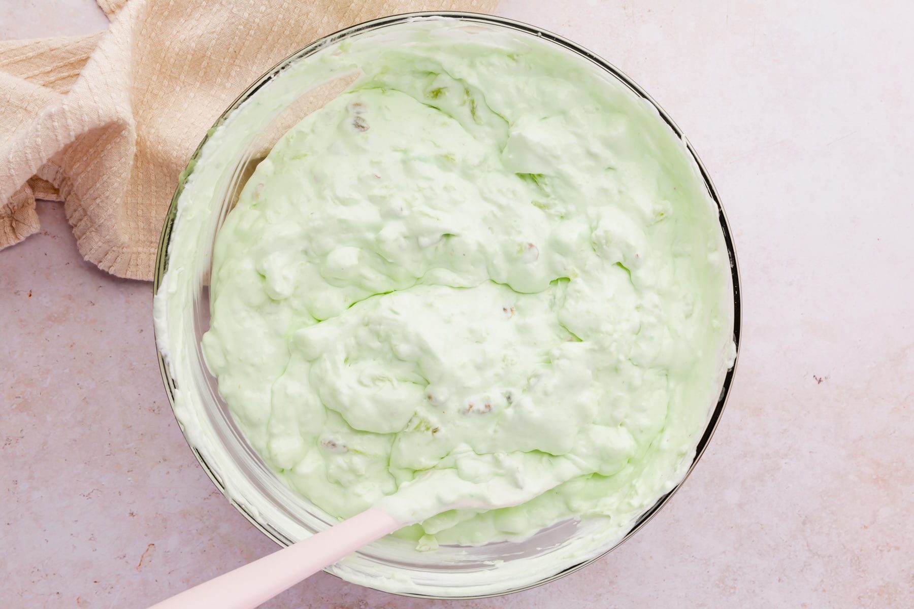 A bowl of pistachio fluff with a pink spatula.