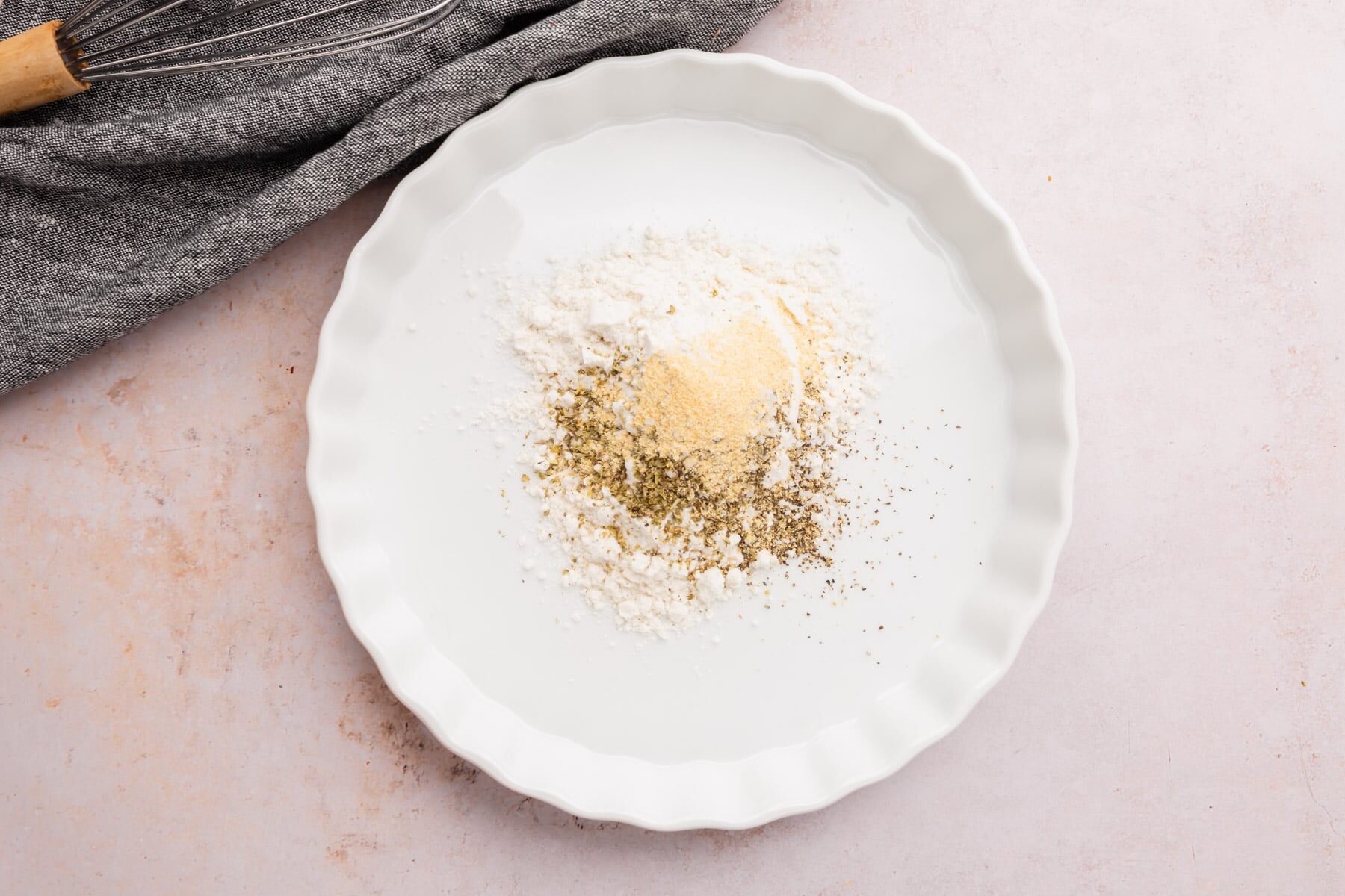 A bowl of gluten-free flour blend, salt, pepper, Italian seasoning, and garlic powder.