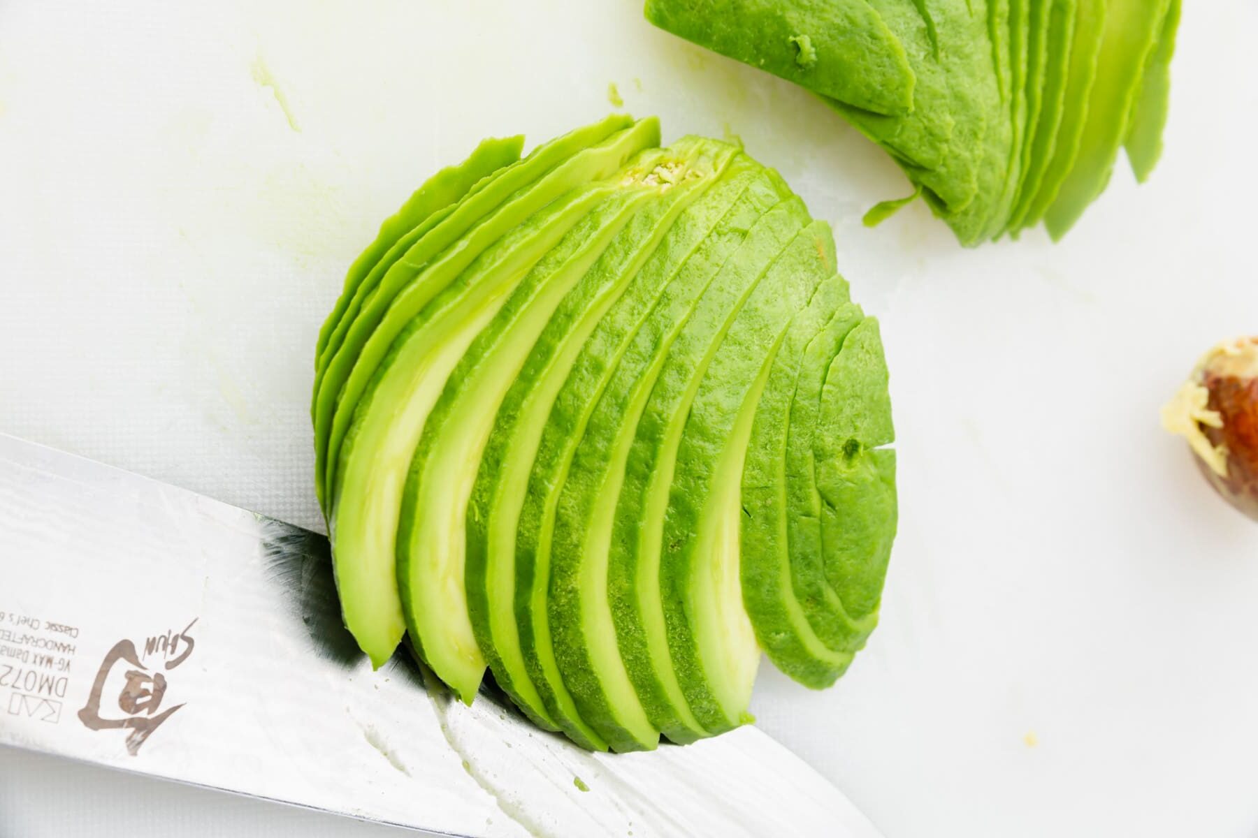 Half of an avocado sliced lengthwise with a chef's knife.