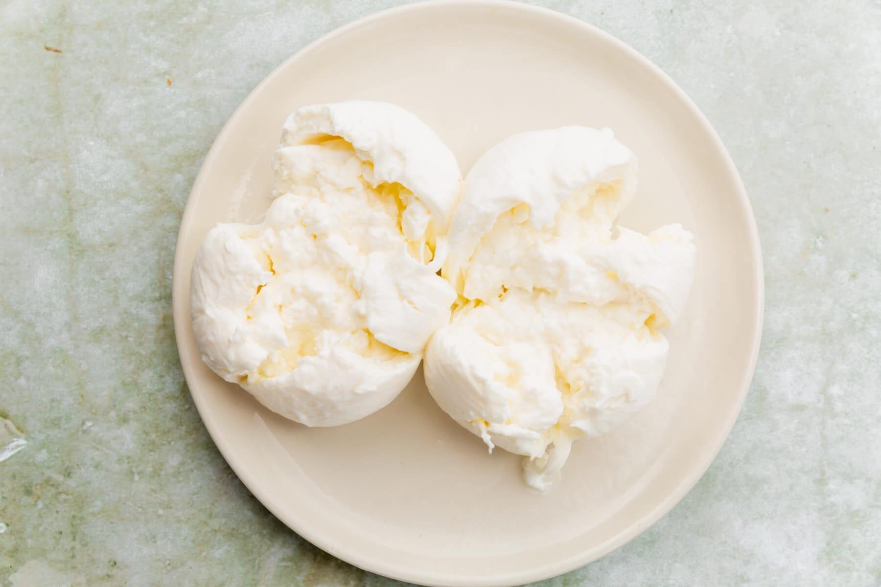 A plate of burrata that has been cut open to reveal the creamy center.