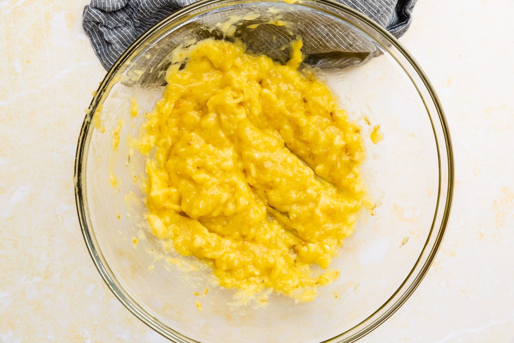 Mashed bananas in a glass mixing bowl.