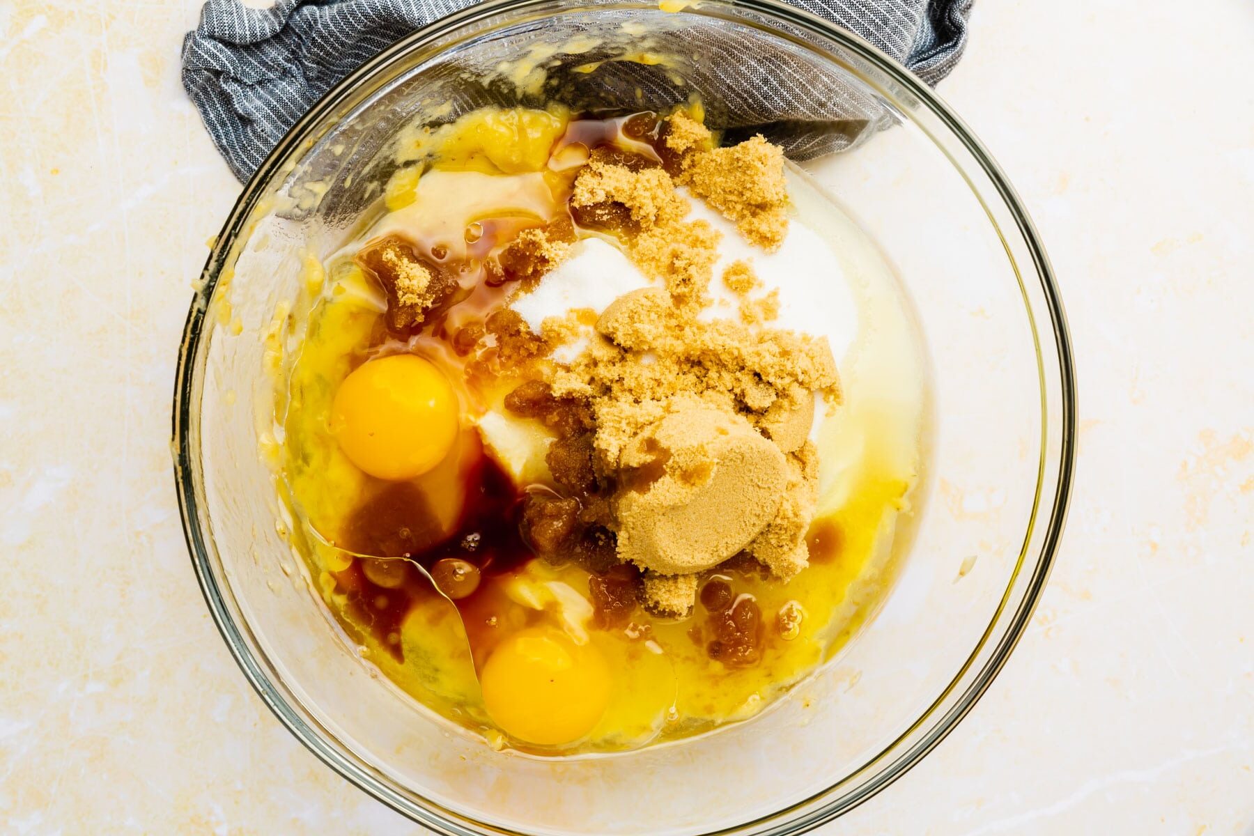 Brown sugar, oil, granulated sugar, vanilla, and eggs in a glass mixing bowl.