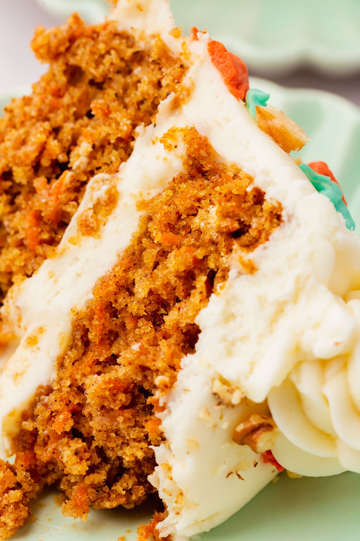 A slice of carrot cake and cream cheese frosting on its side on a plate.