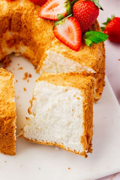 A close up of a slice cut off from a gluten-free angel food cake topped with strawberries.