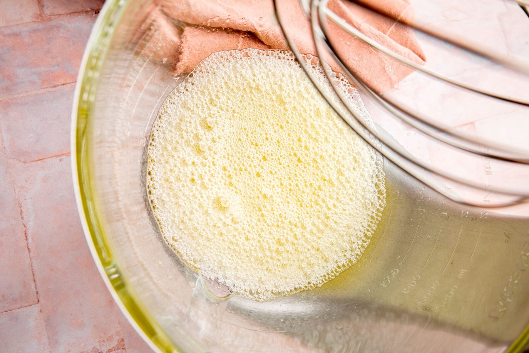 Egg whites in a glass mixing bowl that have been lightly frothed with a whisk.