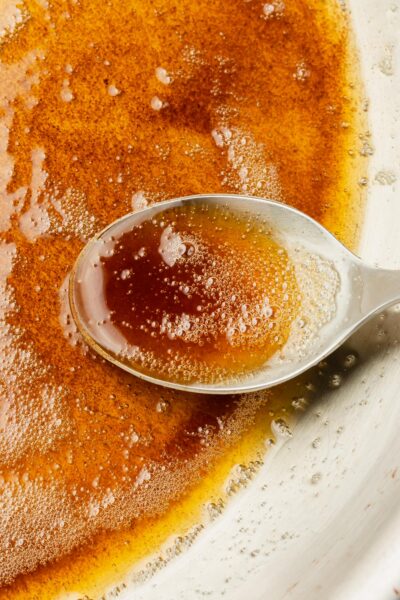 A closeup of a spoon filled with browned butter.