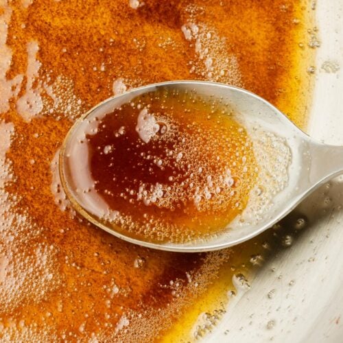 A closeup of a spoon filled with browned butter.