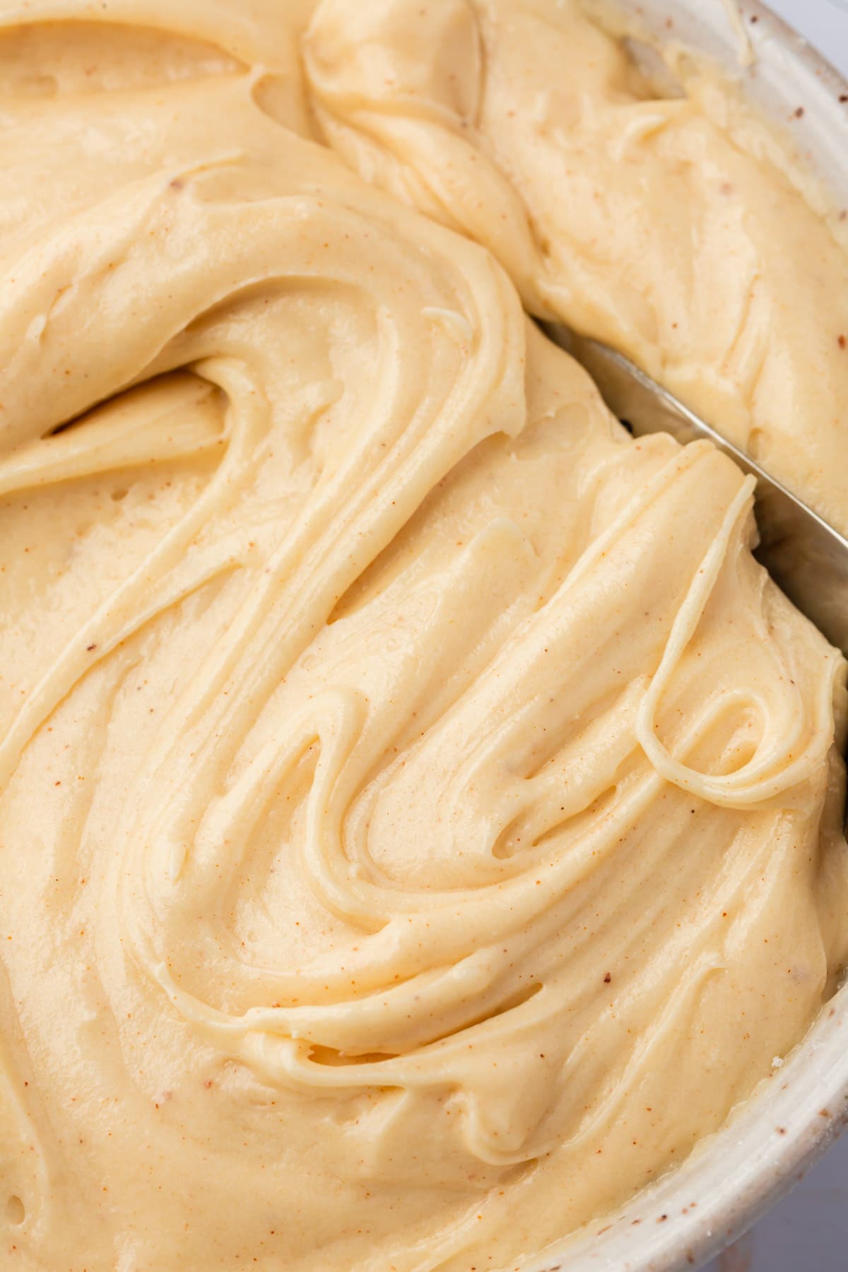 Brown butter cream cheese frosting swirled with a spatula in a bowl.