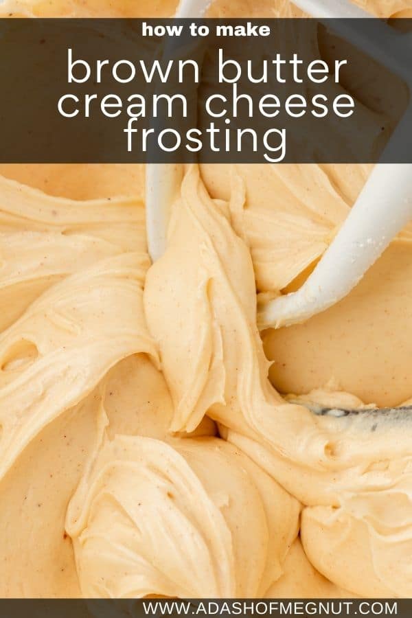 A glass mixing bowl with brown butter cream cheese frosting in it with a paddle attachment from the mixer in the bowl.