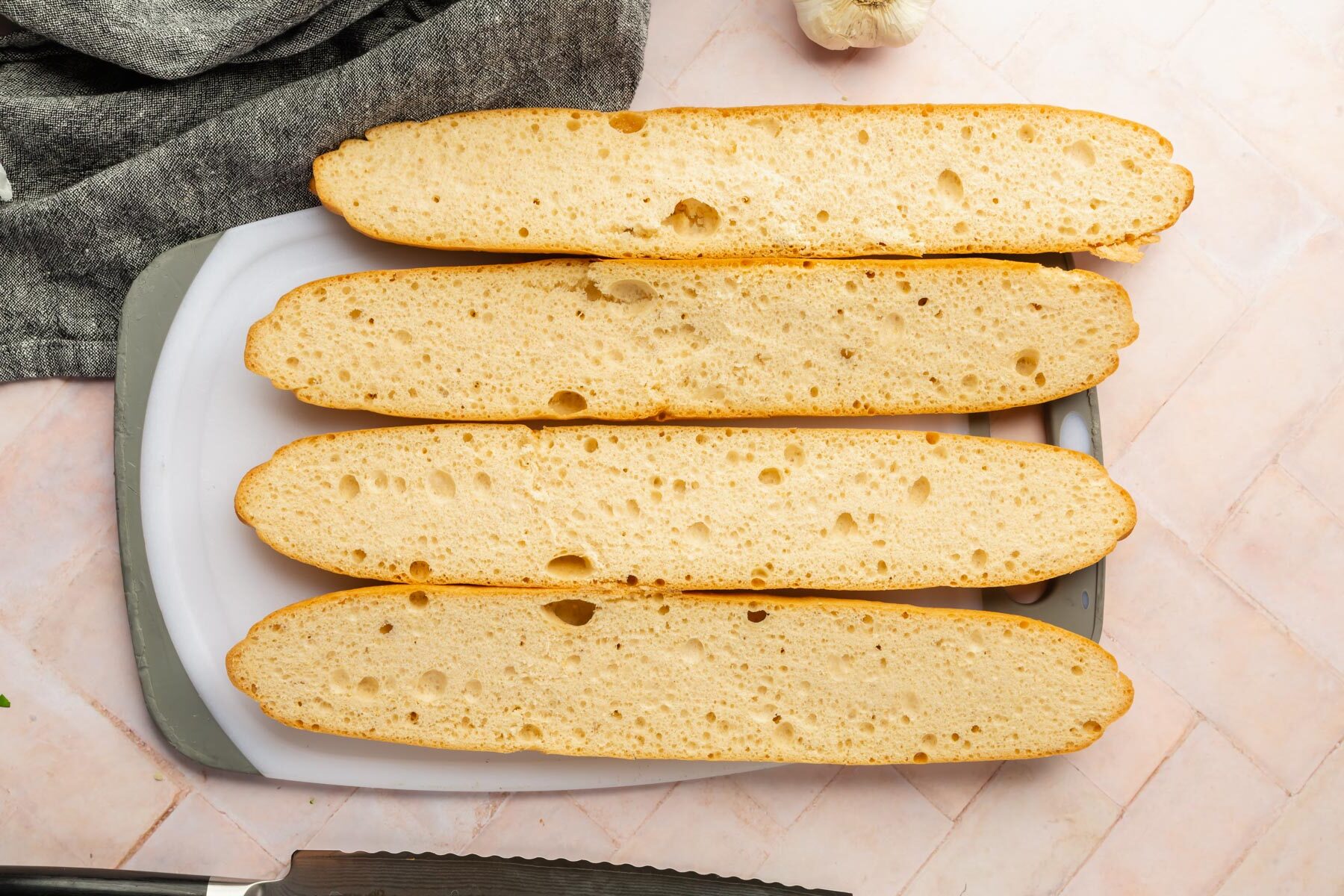 Four baguette halves sliced on a cutting board.