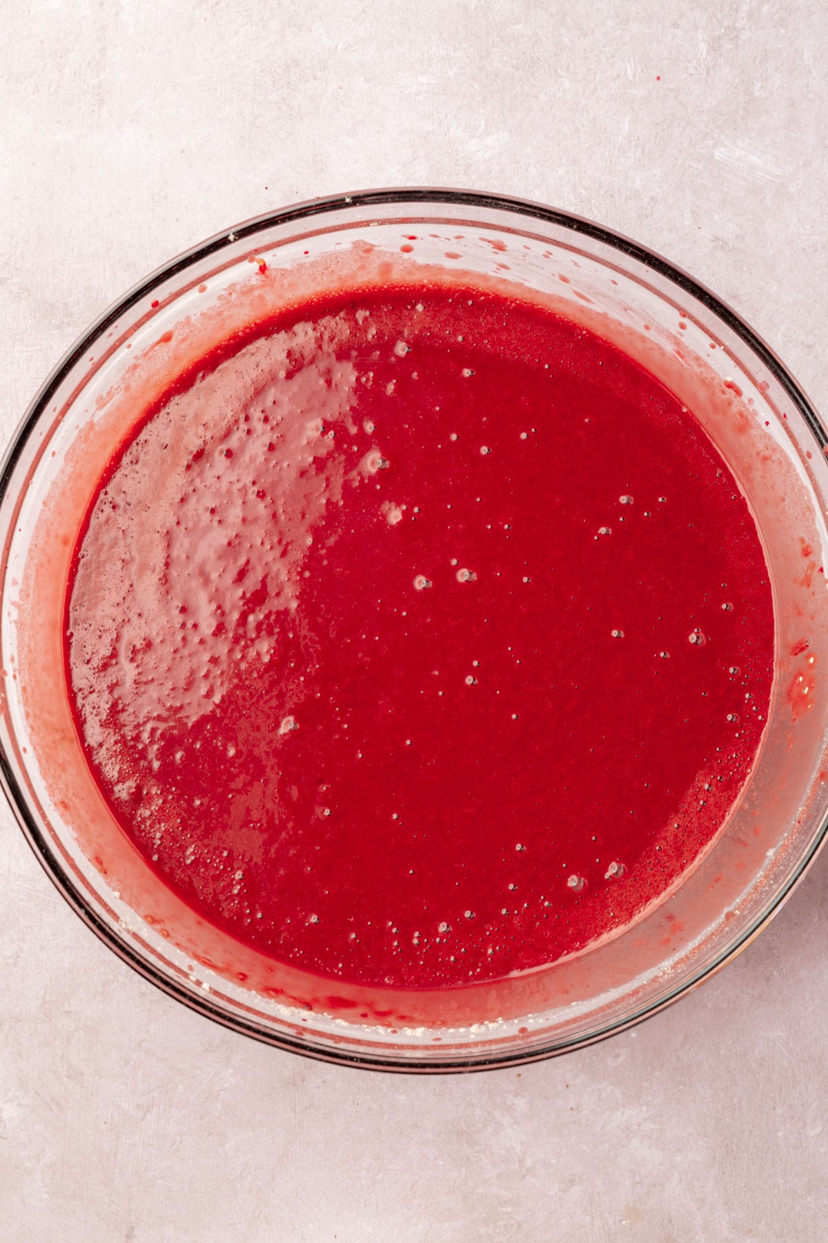 Red velvet cake batter in a glass mixing bowl.