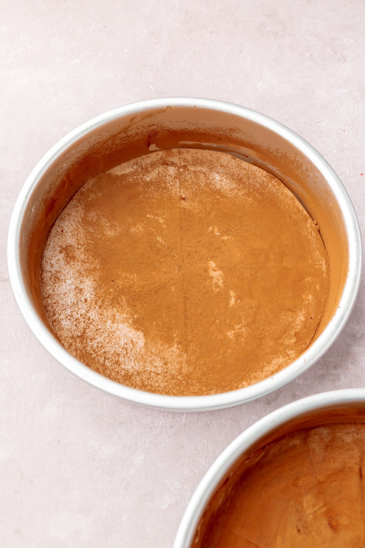 Two round cake pans dusted with cocoa powder.