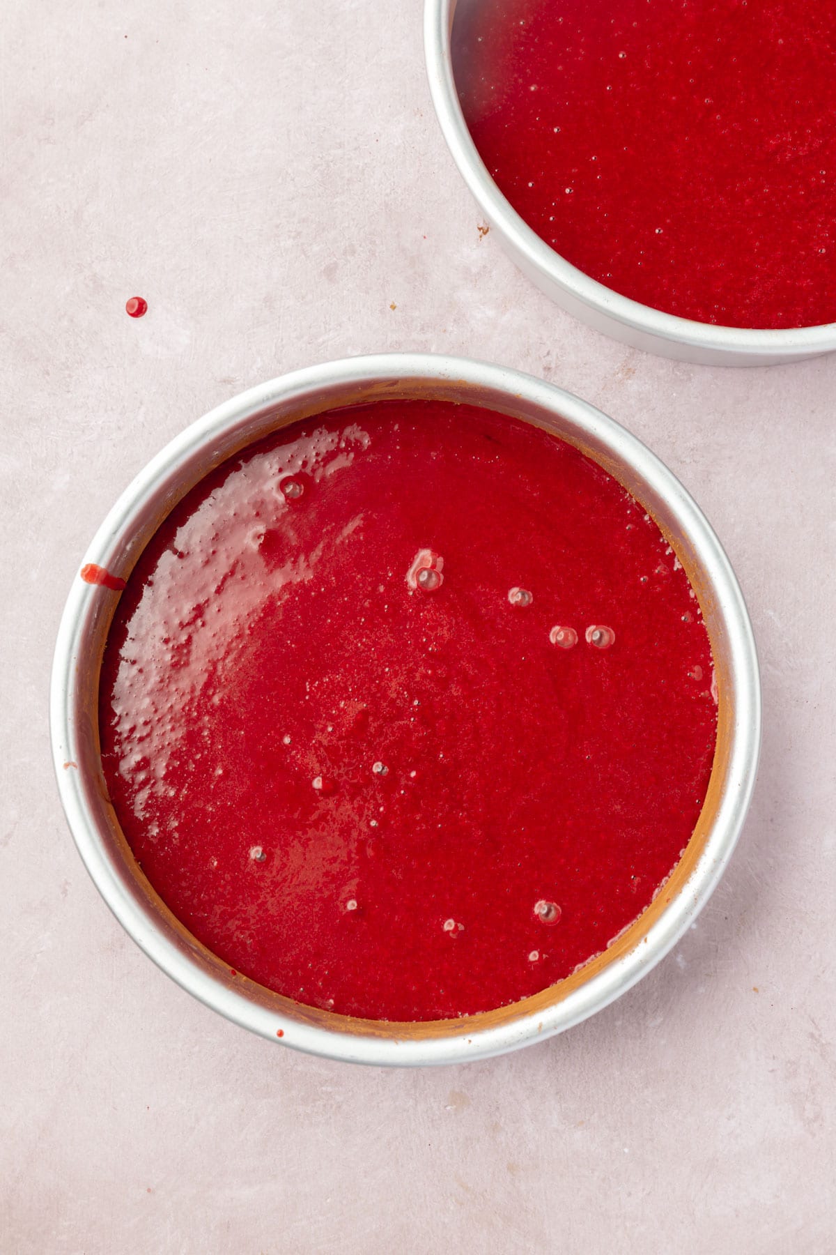 Two round cake pans filled with red velvet cake batter.