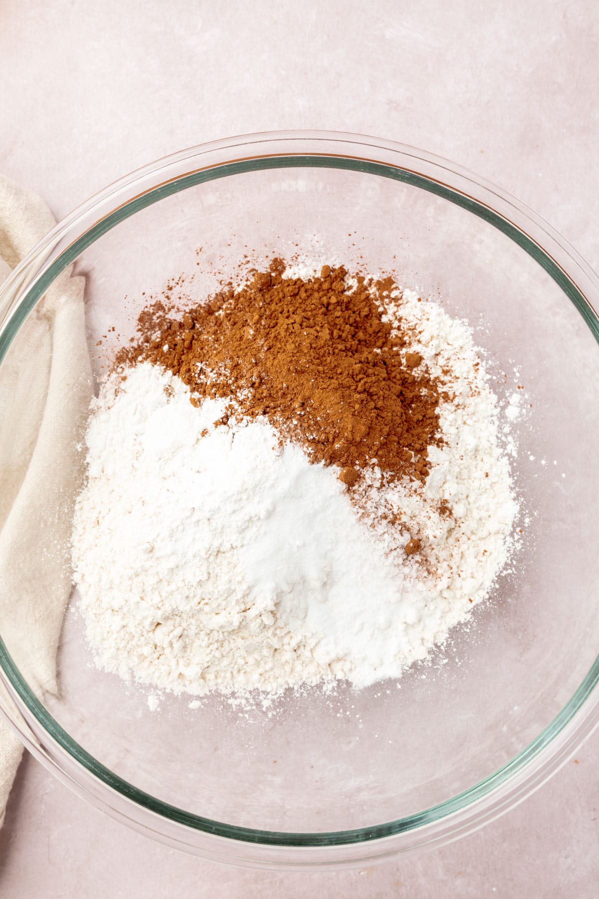 Gluten-free flour, cocoa powder, cornstarch, baking powder, and baking soda in a glass mixing bowl.