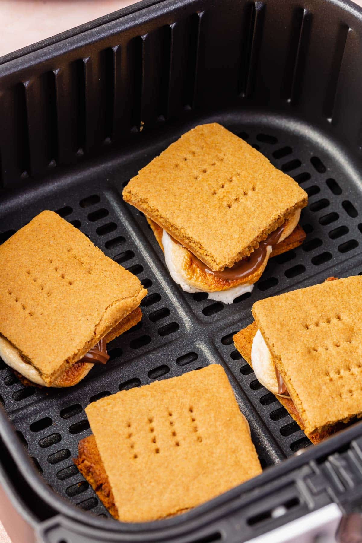 An air fryer basket filled with four s'mores.