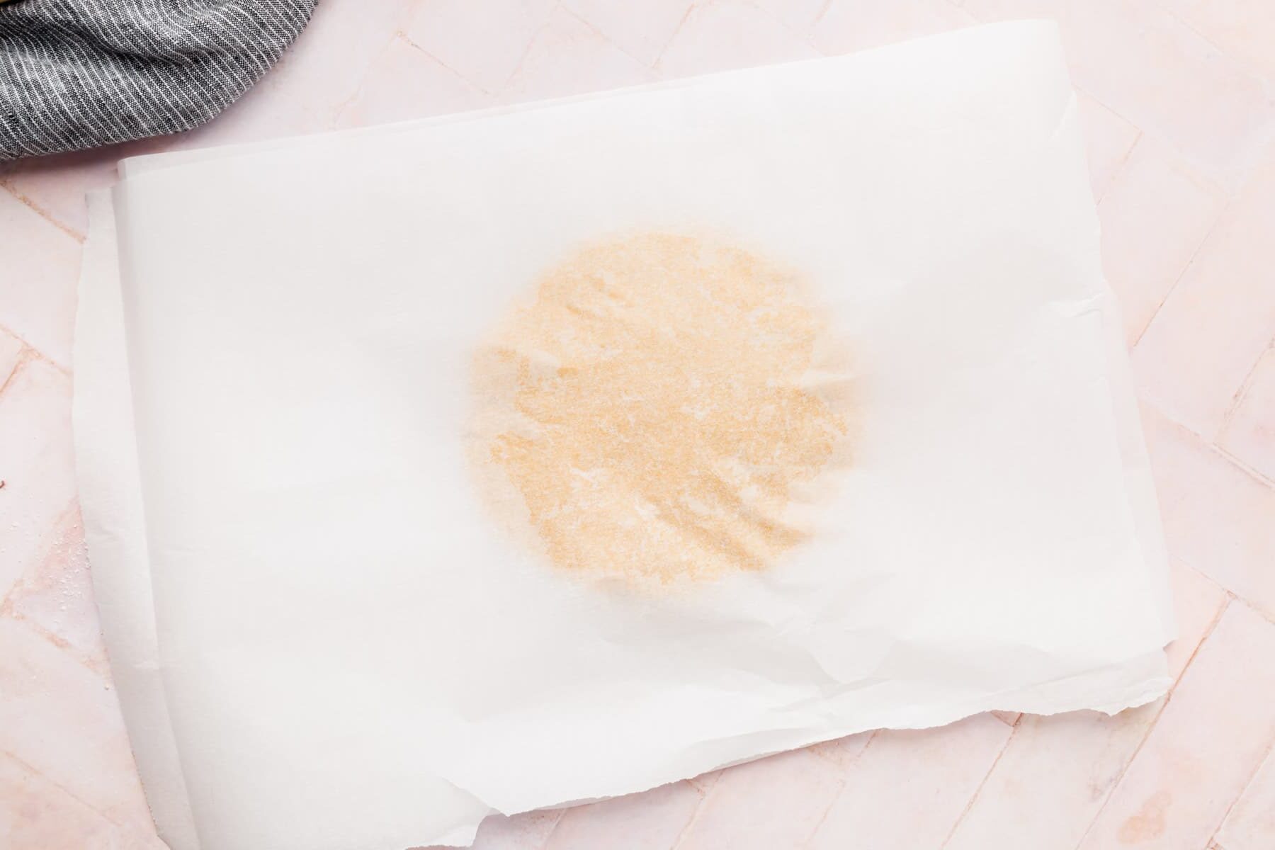 A round piece of graham cracker dough covered by a piece of parchment paper.