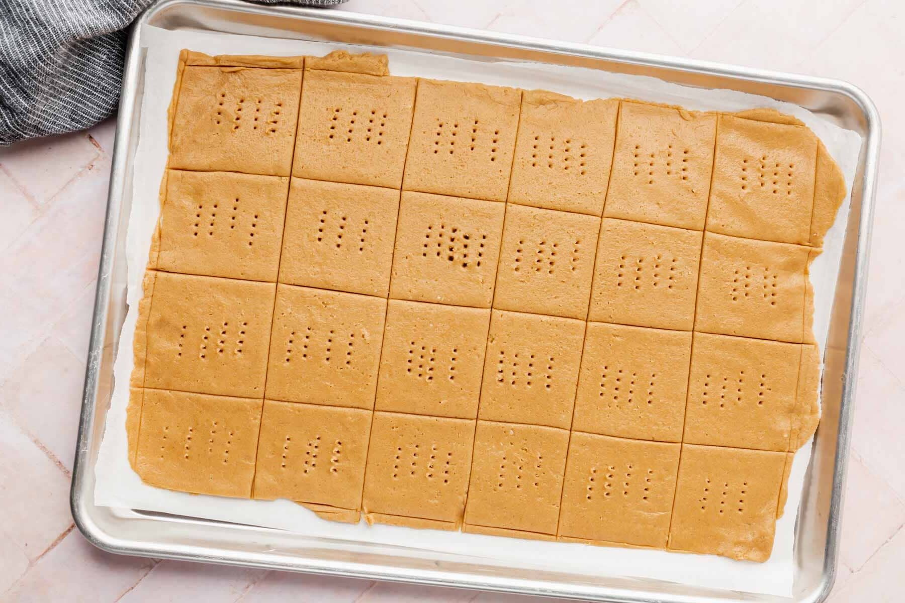 Graham cracker dough cut into squares on top of a baking sheet ready for baking.