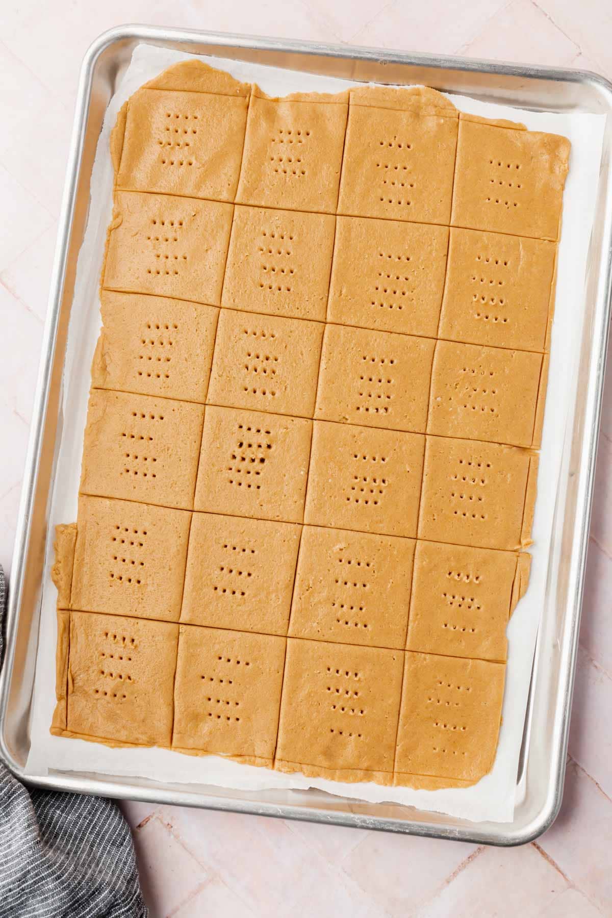 Graham cracker dough cut into squares on top of a baking sheet ready for baking.