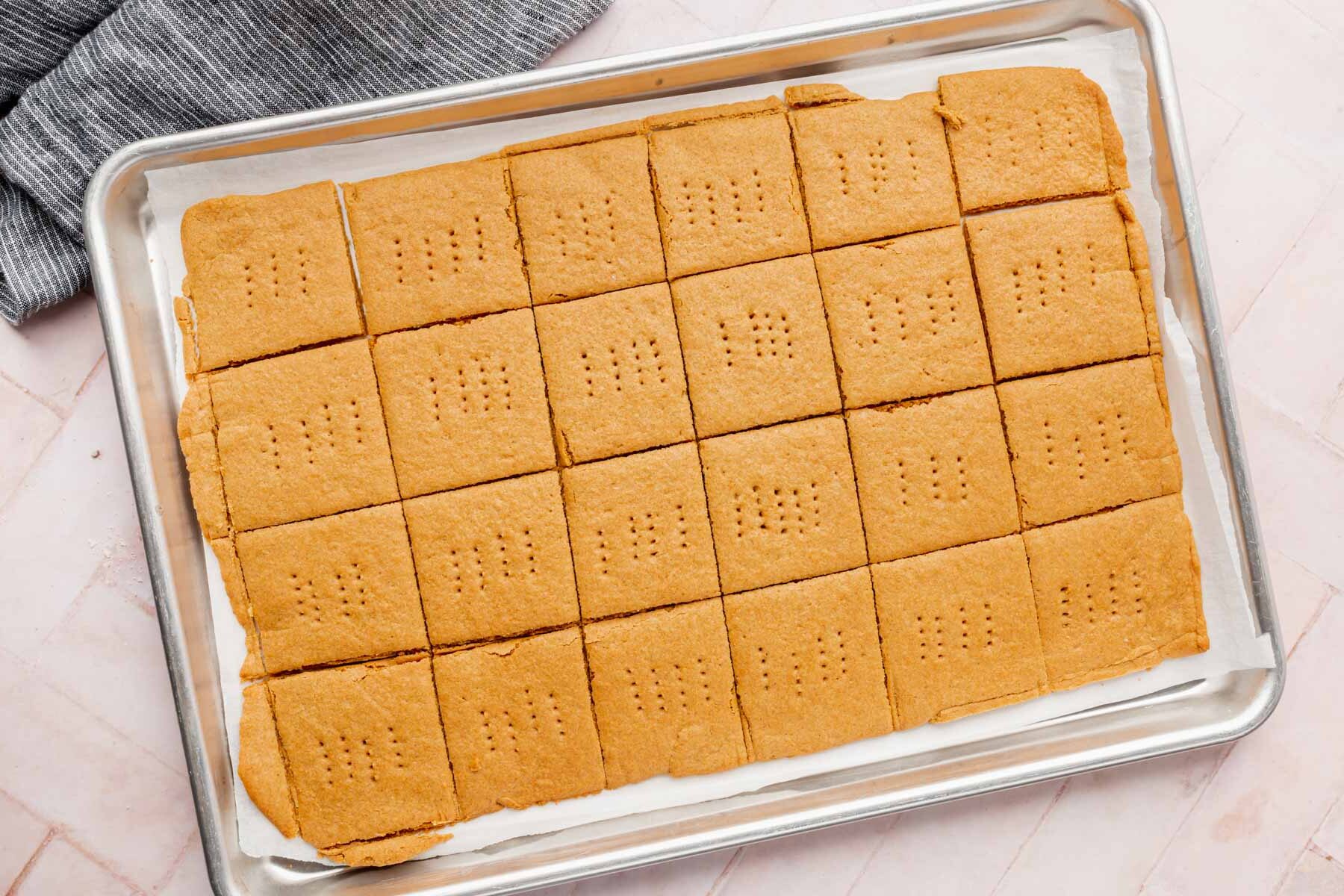 Baked graham crackers that have been scored with a knife on a baking sheet.