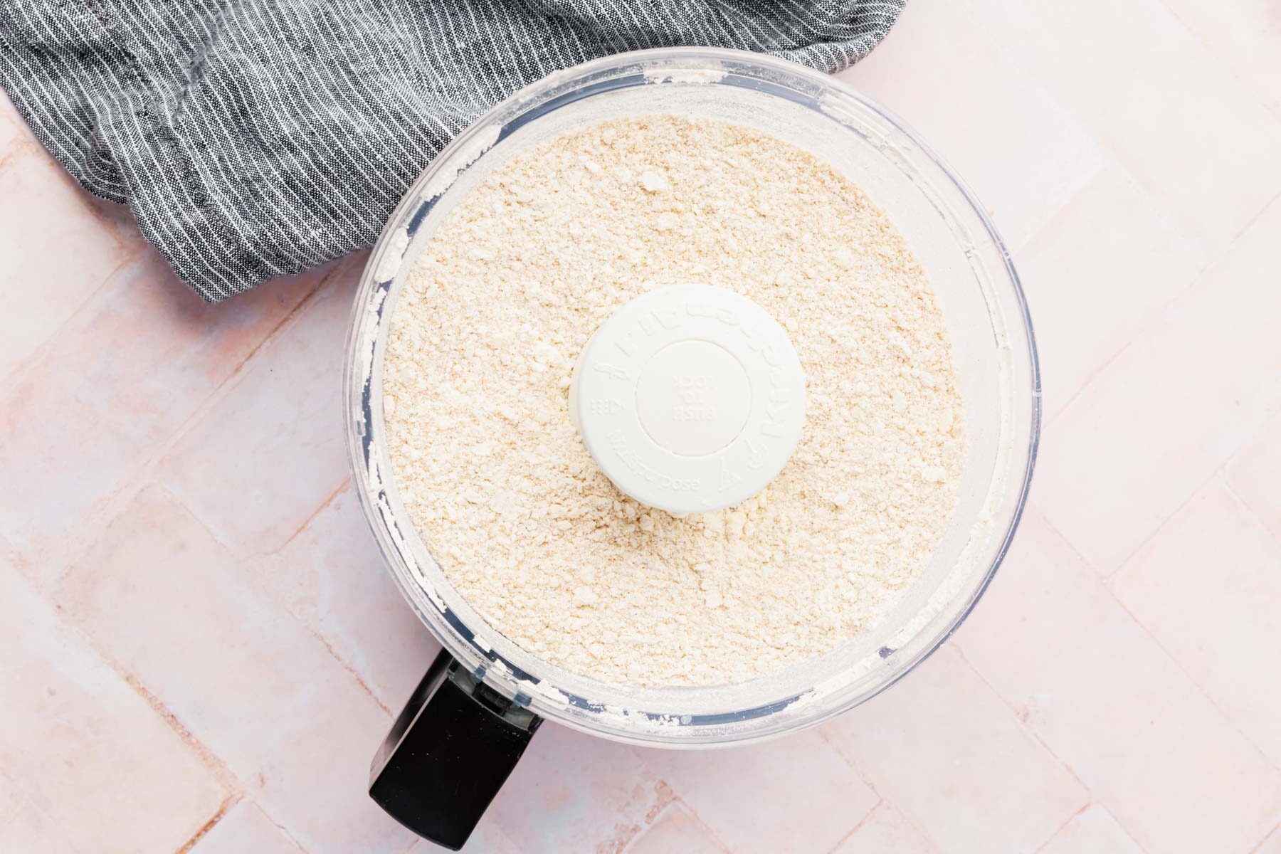 A food processor with gluten-free flour and butter chunks in it.