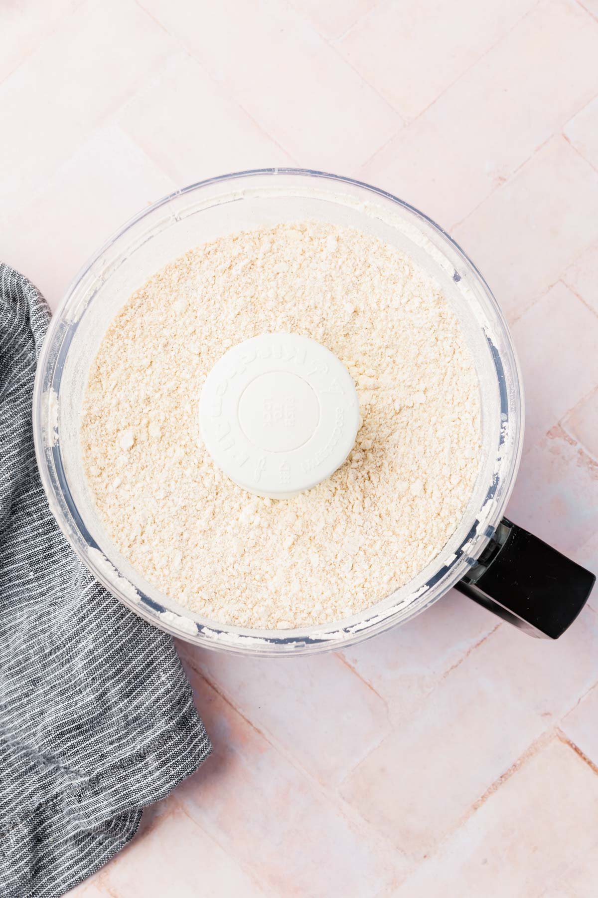 A food processor of gluten-free flour and small bits of butter in it. 