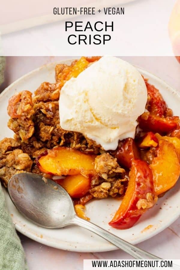 A single serving of gluten-free peach crisp on a small plate topped with a scoop of vanilla ice cream and a spoon next to it.